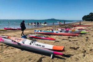 Activity at Mairangi Bay, beach with lots of Kayaks sitting on the sand.